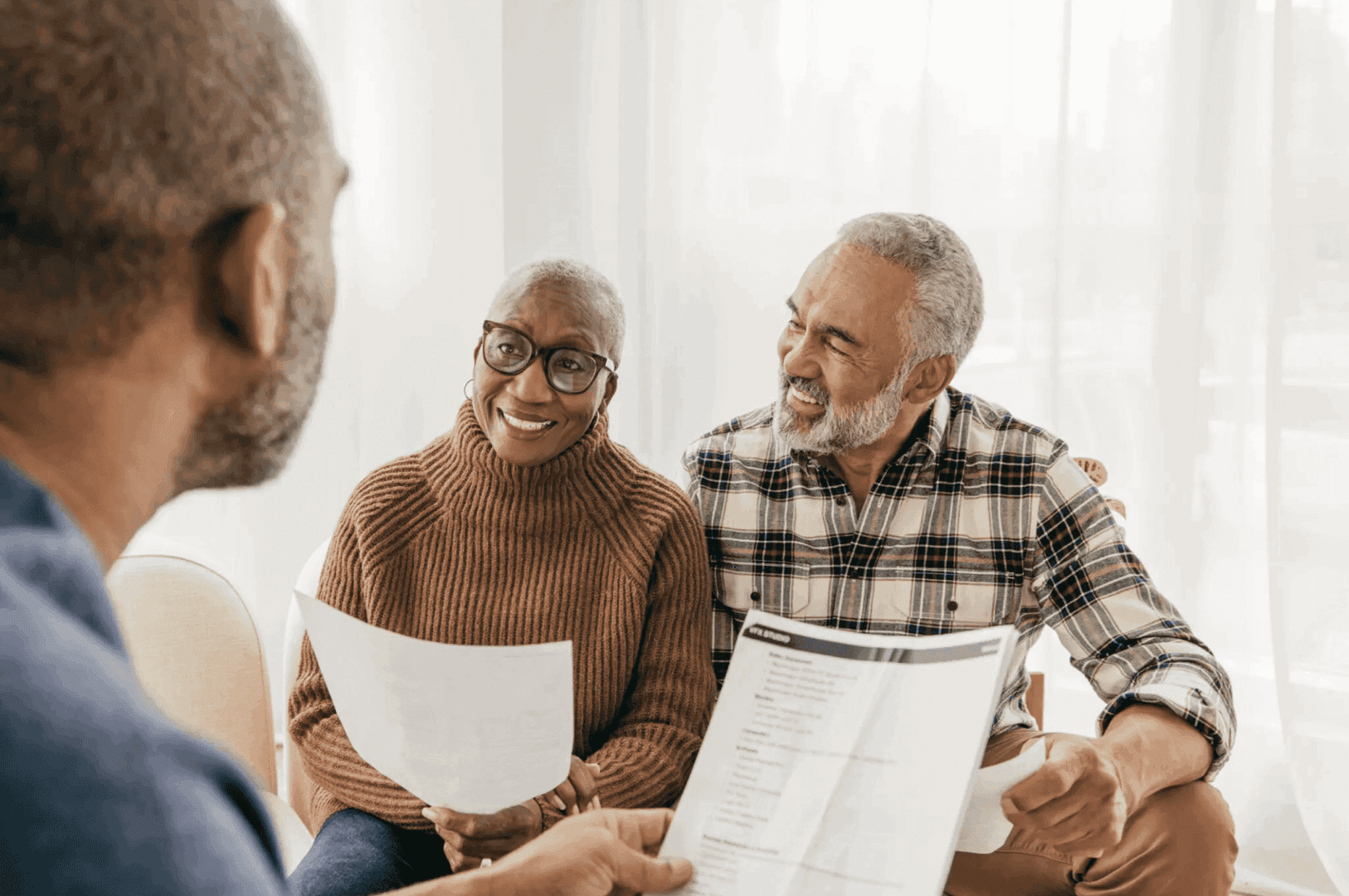 Two elderly people discussing documents with a professional.
