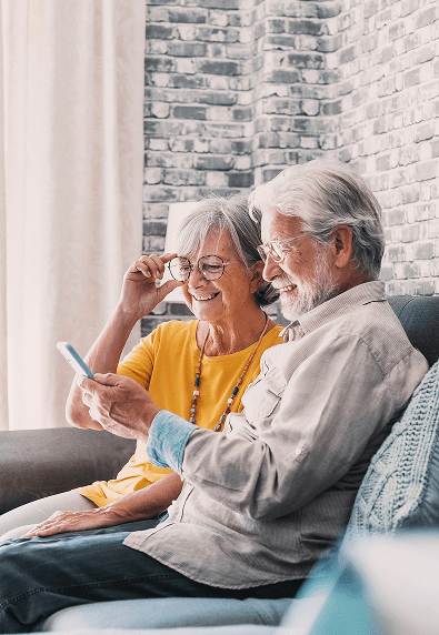 Elderly couple smiling and using smartphone together.