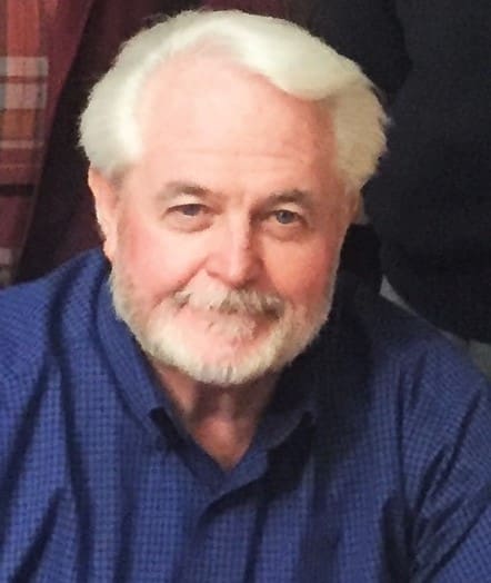 Portrait of an elderly man with white hair and beard, smiling gently.