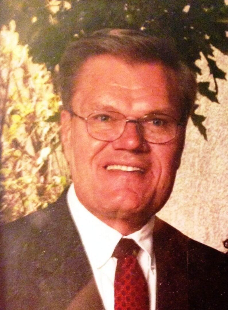 Portrait of a smiling elderly man in glasses and a suit.