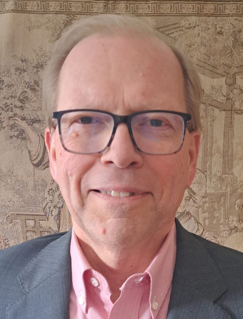 Portrait of an older man wearing glasses and a suit jacket.
